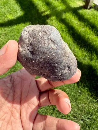 The smooth purplish-grey face of the small ambergris piece, held in hand